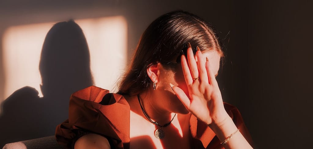 A woman sitting in a chair with her hands on her face-Can Trauma Be Passed Down Through Generations?
