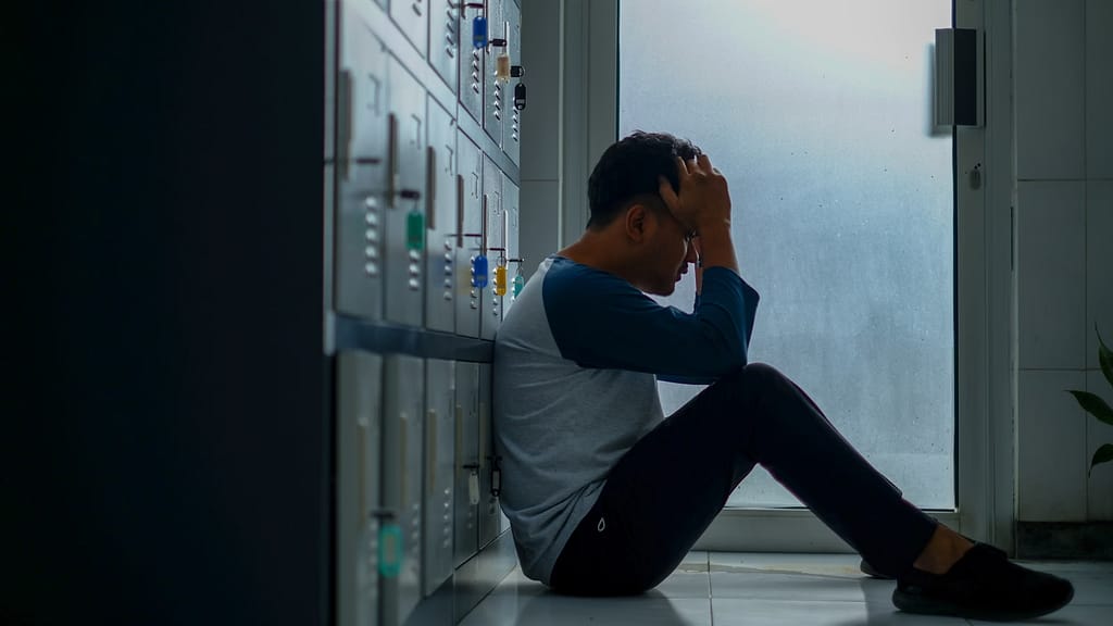 man in gray long sleeve shirt and black pants sitting on white floor tiles-How to Fix the Effects of Stress on Your Body