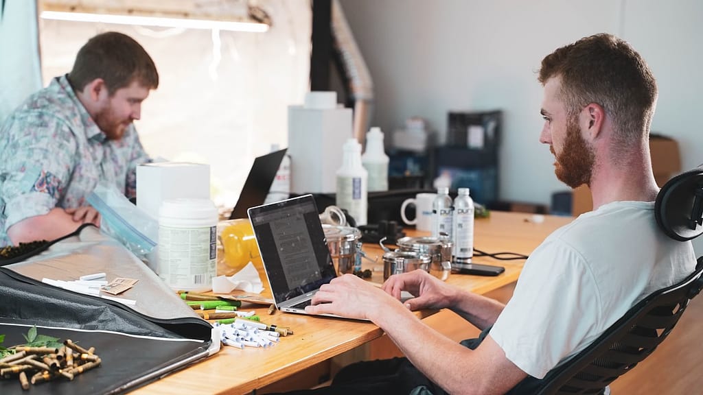 a man sitting at a desk with a laptop and another man sitting at a desk with a computer-How to Lose Weight Without Going to the Gym