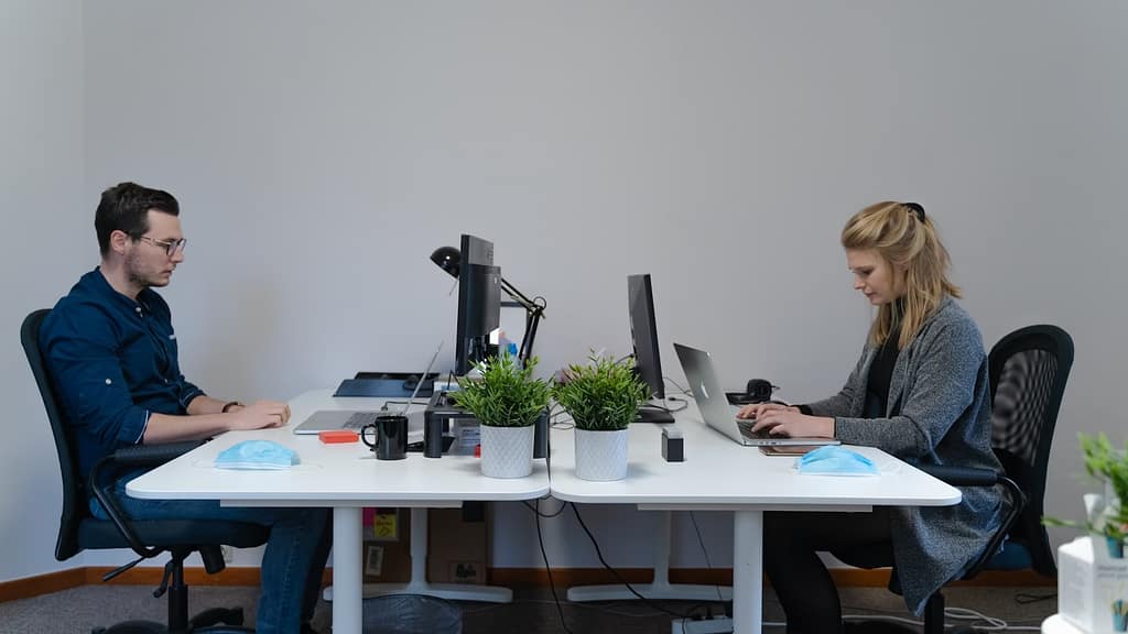 man and woman sitting at the table using computers