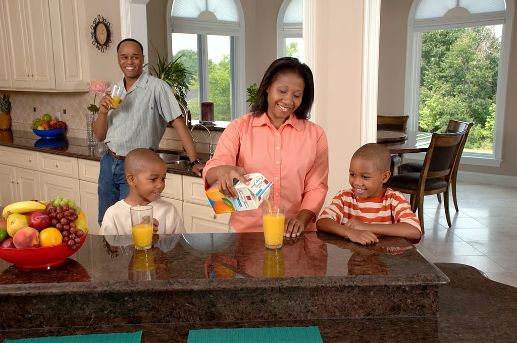 man, woman, and two boys inside kitchen drinking orange juice-How to Optimize Metabolic Health Naturally