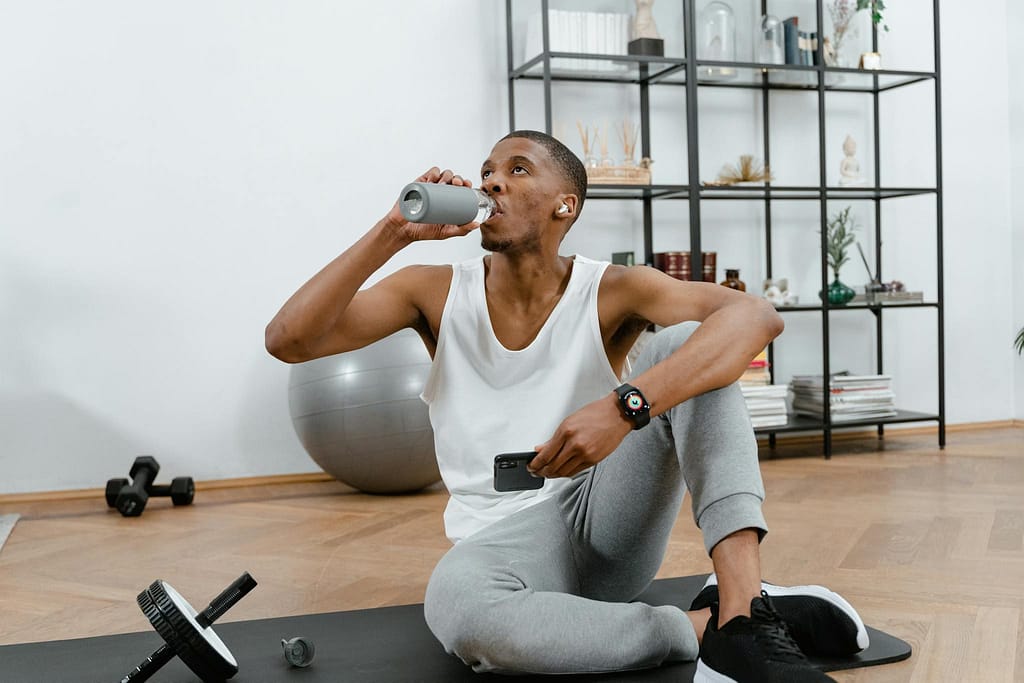 a man in a home gym drinking water for good health