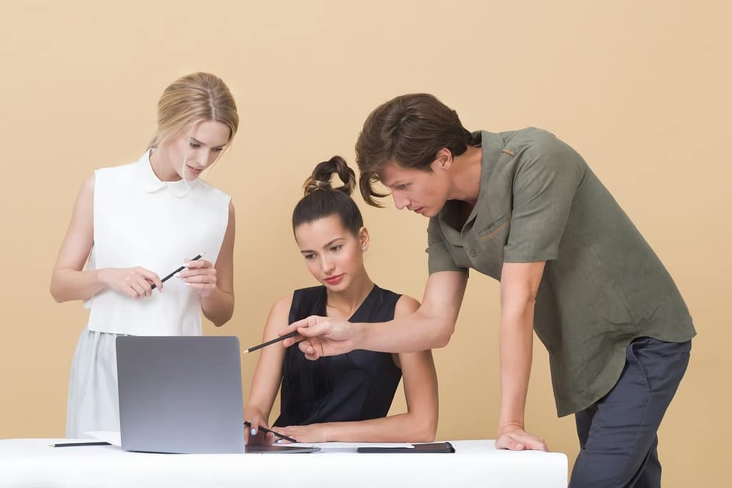 man teaching women while pointing on gray laptop