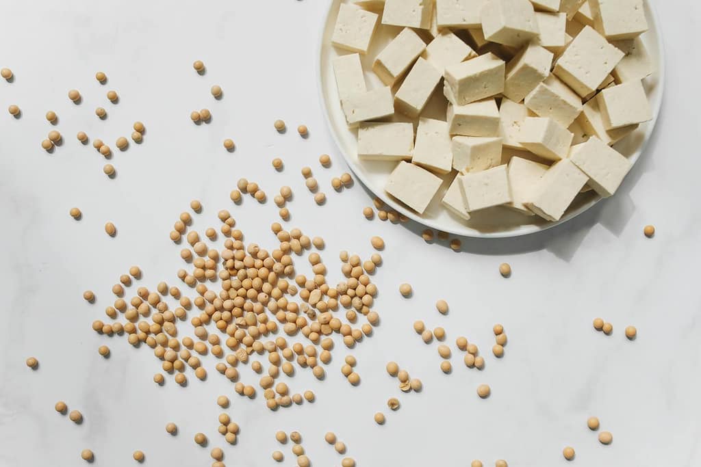 Flat lay of tofu cubes and soybeans scattered on a white marble surface. High Blood Pressure Medications Alternatives You Should Know
