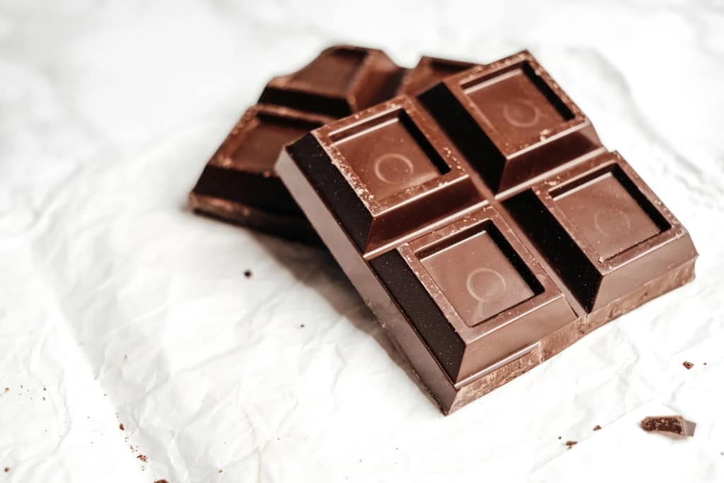 Pieces of brown chocolate on a white surface.