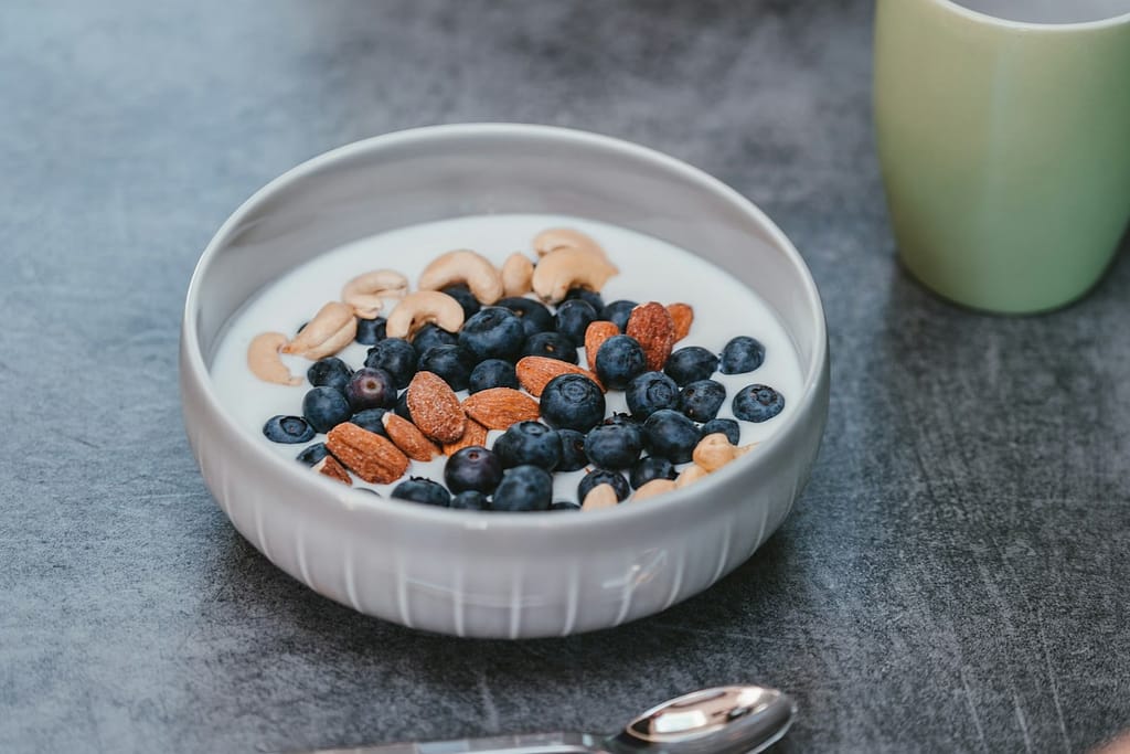 white ceramic bowl of yogurt with blue berries and nuts-Whole-Fat Dairy Makes a Comeback: What You Need To Know