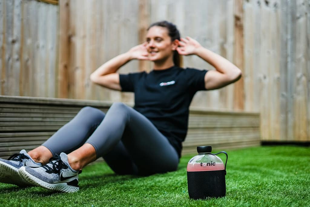 woman in black crew neck t-shirt and black leggings working out on a green grass field-Safe Workout Plans for New Moms You Should Know