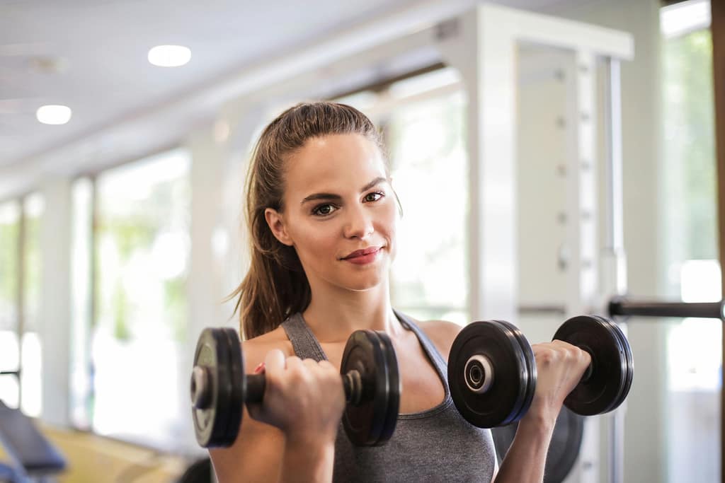 Woman in Gray Tank Top Holding Two Black Dumbbells-How to Use the 3-3-3 Rule for Insane Gym Focus and Growth