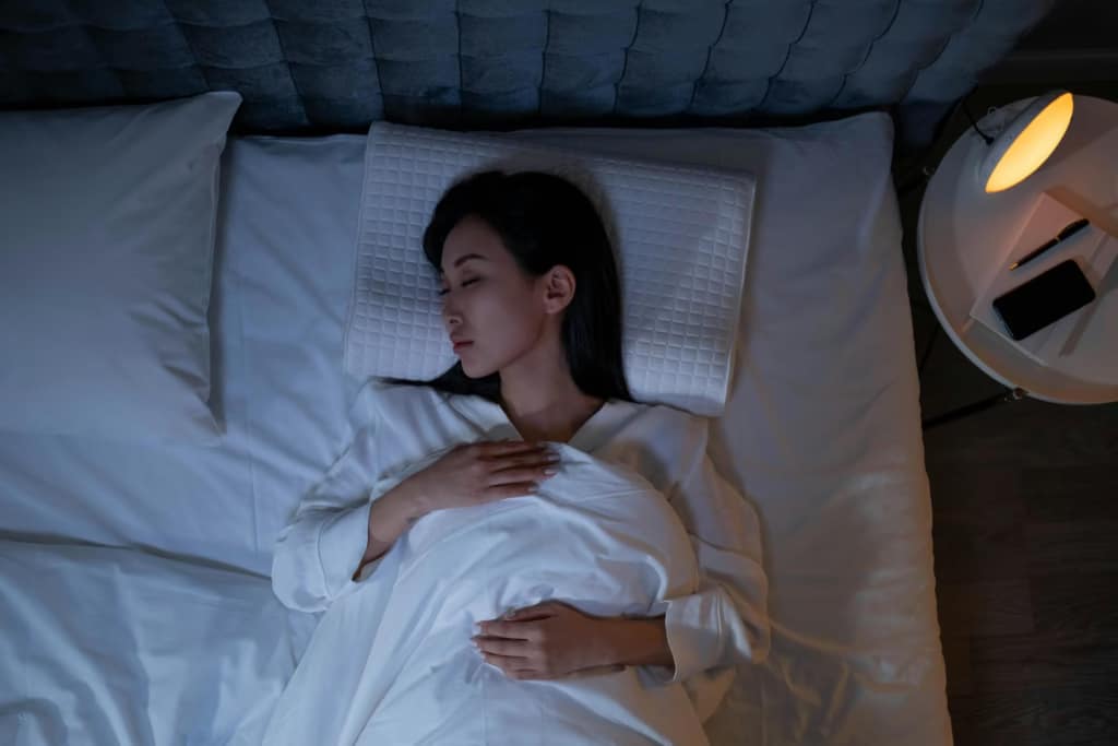 An image of a woman sleeping on a bed at home