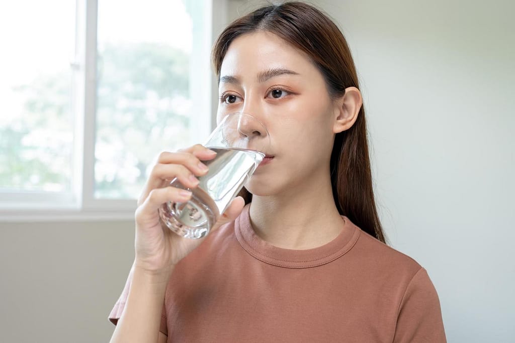 A woman drinking a glass of water-How to Reset Your Body in 24 Hours