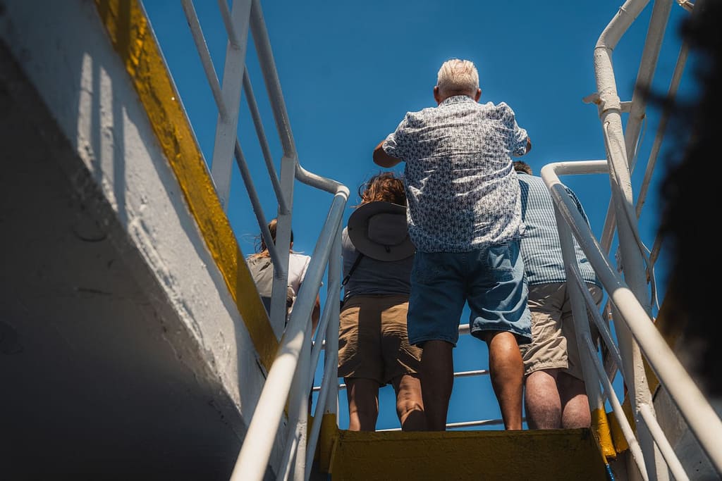 A diverse group of adults climbing yellow stairs outdoors under a clear blue sky.