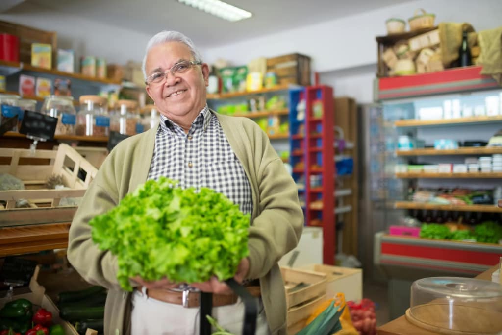 An Elderly Man in Plaid Shirt Holding a Fresh Lettuce