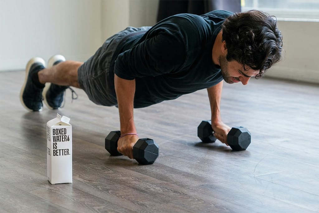 man in black t-shirt and black shorts doing push up with dumbbells