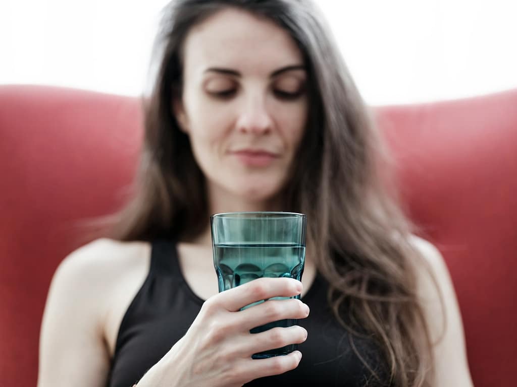 a woman sitting on a couch holding a glass of water-Whole-Fat Dairy Makes a Comeback: What You Need To Know