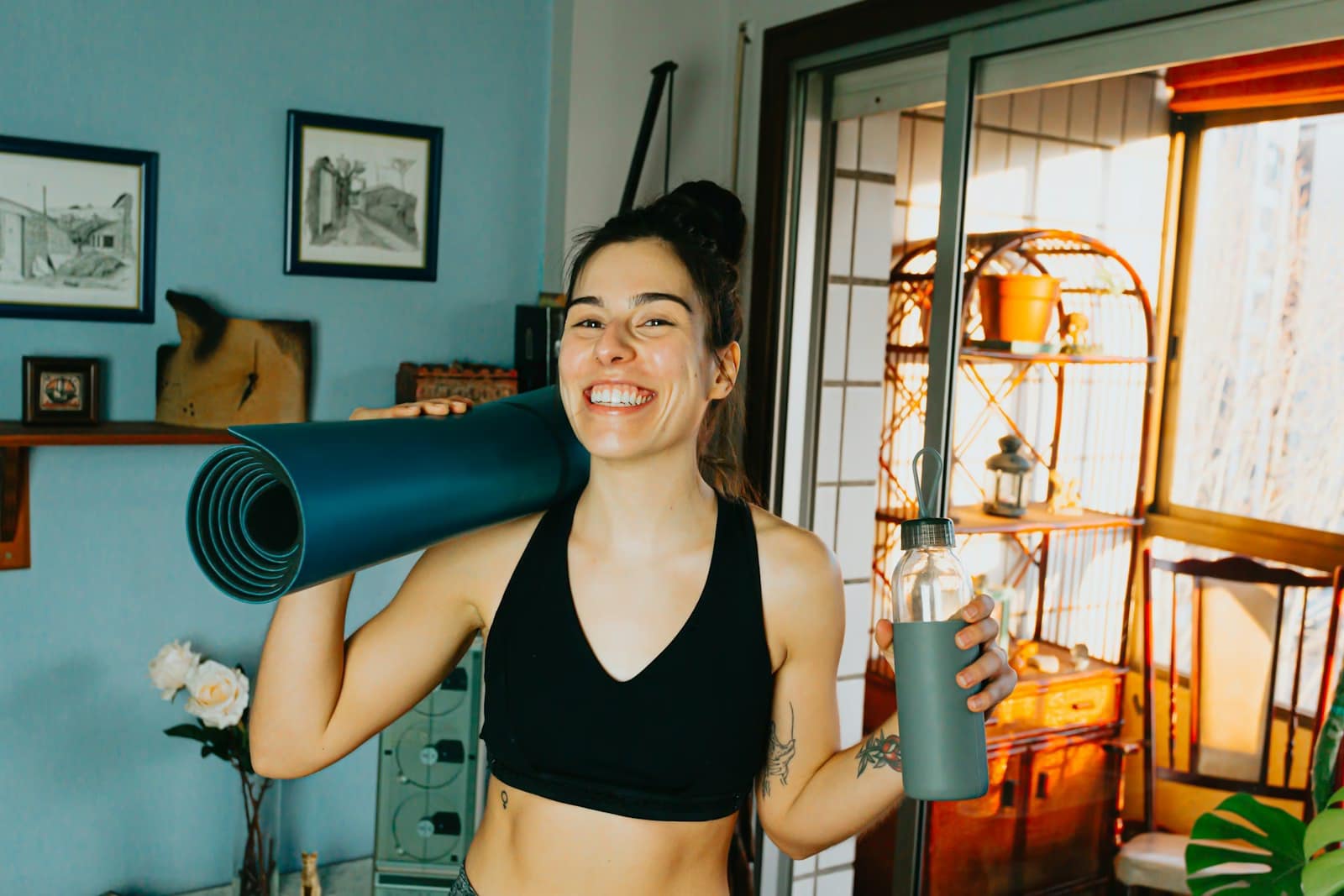 woman in black sports bra holding blue and black tank top getting ready for exercise