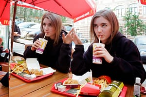 a woman eating processed food at MacDonald's. Another way how sugar destroys your health.