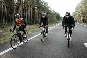 Three cyclists are enjoying a ride on a scenic forest road during the day.