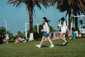 Two young women walk on green grass under palm trees-The Best Cardio Workouts for Burning Fat Fast