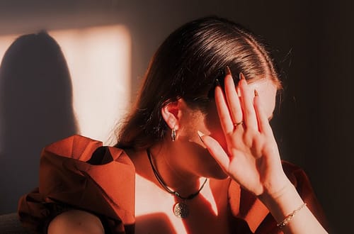 A woman sitting in a chair with her hands on her face-Can Trauma Be Passed Down Through Generations?