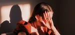 A woman sitting in a chair with her hands on her face-Can Trauma Be Passed Down Through Generations?