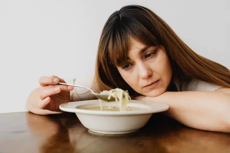 A woman eating noodles sou. Important Facts About Extreme Calorie Restriction You Need to Know